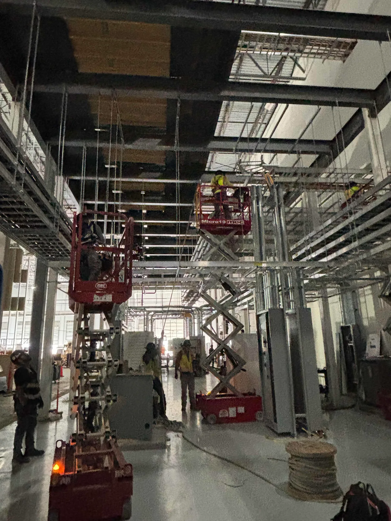 Crews installing overhead systems from elevated work platforms