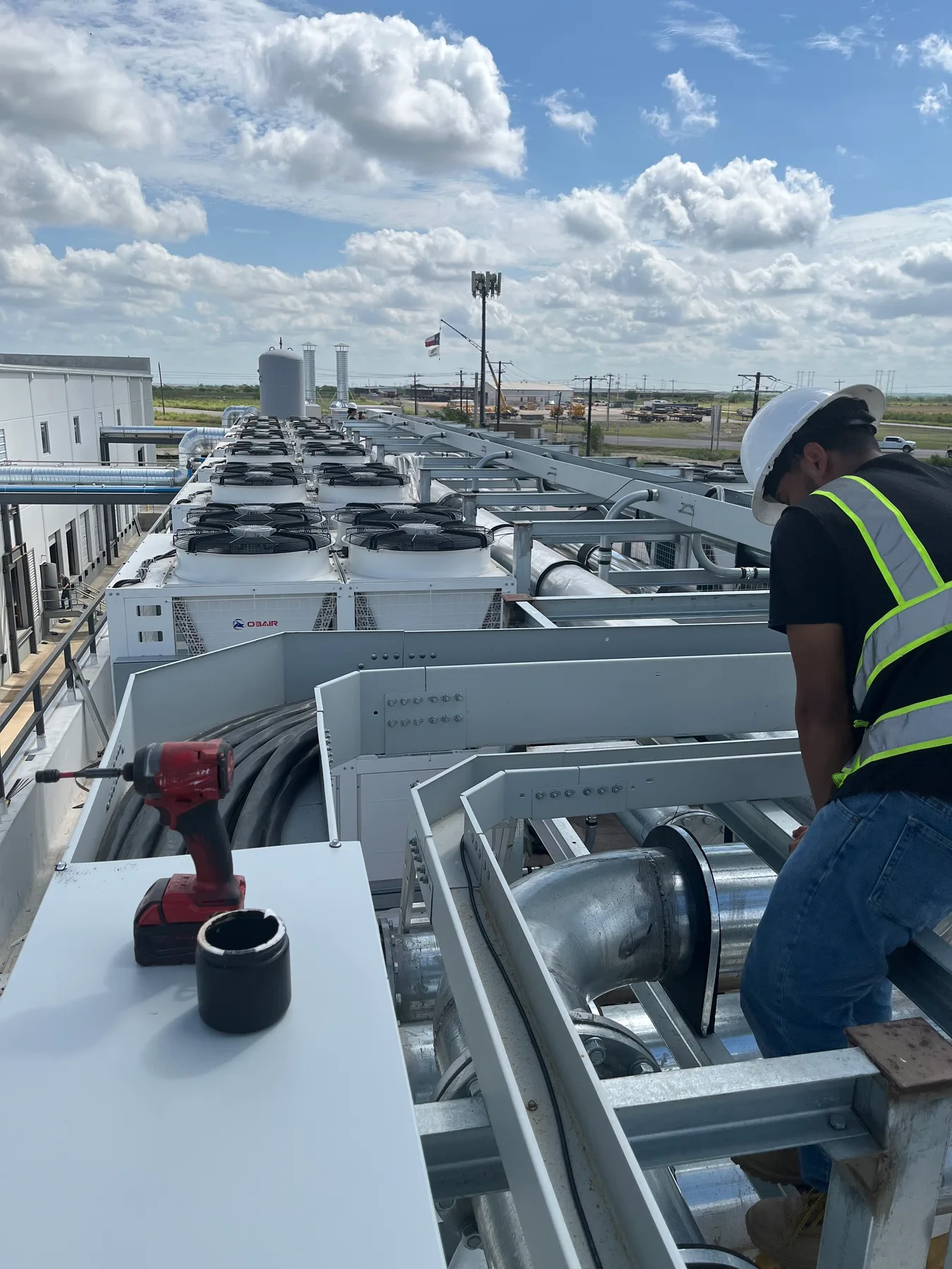 Electrical installation beside rooftop equipment, worker facing downward