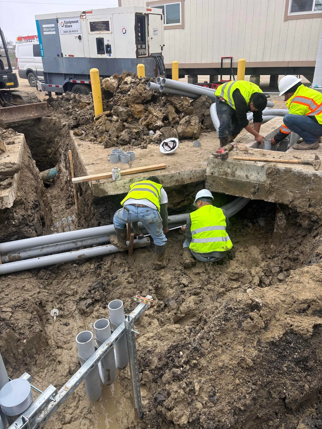 Crew installing underground conduit with faces turned away